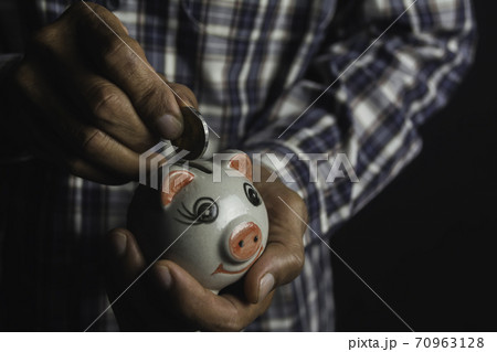 Saving money concept and hand putting money coin into piggy bank. Accounting and business concept. 70963128