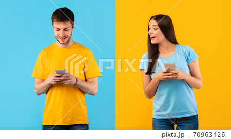 Happy lady and guy using mobile phone at studio 70963426