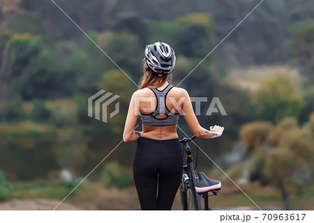 Fit young woman wearing sportswear standing with her bicycle on rocky background Fit young woman wearing sportswear standing with her bicycle on rocky background 70963617
