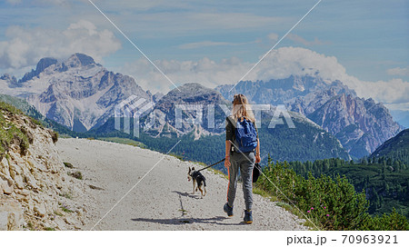 young woman and her dog hiking to the top of a mountain. Pandemic covid isolation young woman and her dog hiking to the top of a mountain. Pandemic covid isolation 70963921