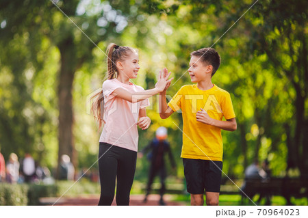 Sports and fitness in adolescence. Caucasian twins boy and girl run on the jogging track in the city park. Two children brother and sister for 10 years running on a rubberized outdoor treadmill Sports and fitness in adolescence. Caucasian twins boy and girl run on the jogging track in the city park. Two children brother and sister for 10 years running on a rubberized outdoor treadmill 70964023
