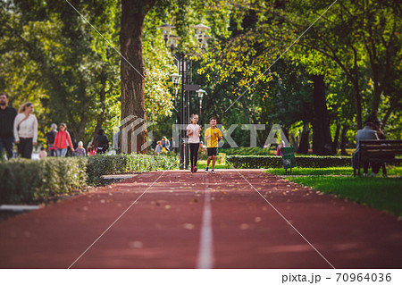 Sports and fitness in adolescence. Caucasian twins boy and girl run on the jogging track in the city park. Two children brother and sister for 10 years running on a rubberized outdoor treadmill Sports and fitness in adolescence. Caucasian twins boy and girl run on the jogging track in the city park. Two children brother and sister for 10 years running on a rubberized outdoor treadmill 70964036
