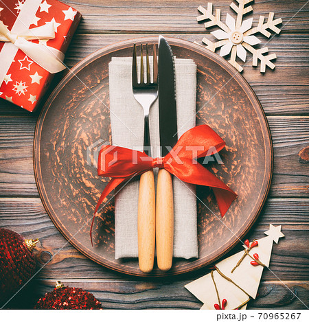 Top view of plate, fork and knife served on Christmas decorated wooden background. New Year Eve concept with copy space Top view of plate, fork and knife served on Christmas decorated wooden background. New Year Eve concept with copy space 70965267