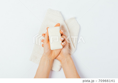 Female hands hold bar of soap above towel Female hands hold bar of soap above towel 70966141