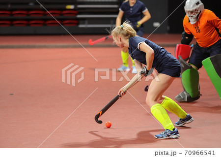 Young woman player in attack at indoor hockey match 70966541
