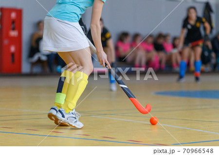 Young woman player in attack at indoor hockey match 70966548