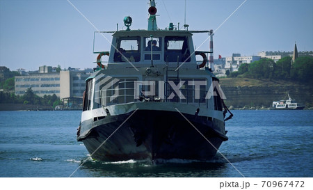 The pleasure boat sails slowly along the bay. The man controls the boat in the control room, the silhouette of a sailor. Beautiful marine technology background The pleasure boat sails slowly along the bay. The man controls the boat in the control room, the silhouette of a sailor. Beautiful marine technology background 70967472