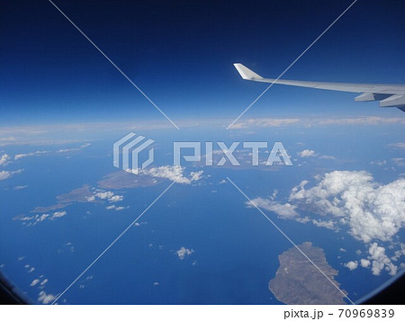 飛行機の翼と空（青い空、白い雲、海と島、日中） 70969839