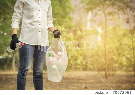 Volunteer woman collecting PET plastic bottle garbage in park for recycle. Volunteer and Save  70972061