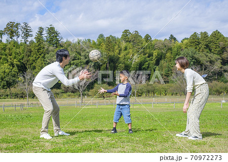公園でボール遊びをする家族の写真素材