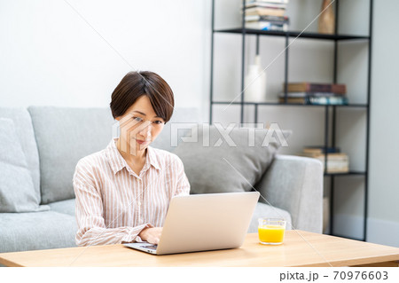 リビングでテレワーク中のミドル女性。 リビングでテレワーク中のミドル女性。 70976603