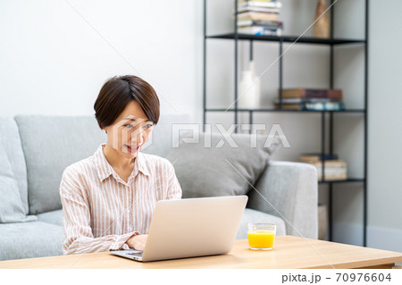リビングでテレワーク中のミドル女性。 リビングでテレワーク中のミドル女性。 70976604