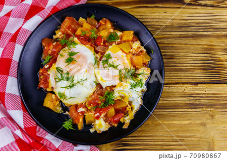 Homemade breakfast shakshuka - fried eggs, onion, bell pepper, tomatoes and dill on rustic wooden table. Jewish cuisine. Top view 70980867
