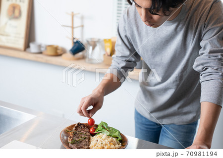 自宅で手料理を盛り付ける若い男性 70981194