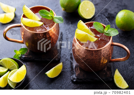 Moscow Mules cocktail with ginger beer, vodka, lime and mint. Grey background. Close up. 70982401