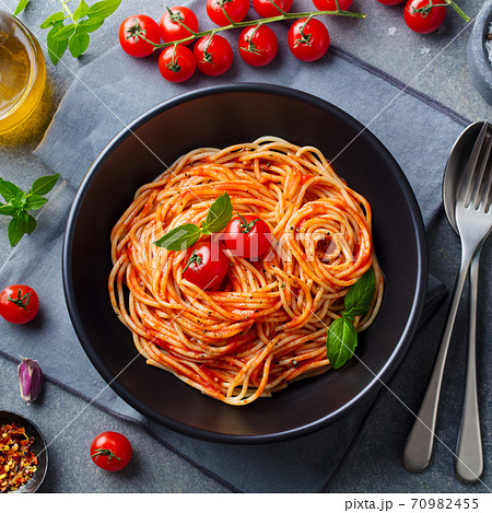 Pasta, spaghetti with tomato sauce in black bowl. Grey stone background. Close up. Top view. Pasta, spaghetti with tomato sauce in black bowl. Grey stone background. Close up. Top view. 70982455