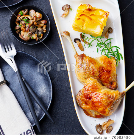 Duck legs confit with potato gratin and mushroom sauce. Top view. 70982480