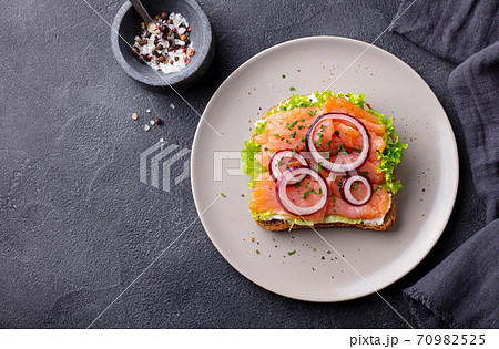 Sandwich with salmon, vegetables and cream cheese on plate. Dark background. Copy space. Top view. Sandwich with salmon, vegetables and cream cheese on plate. Dark background. Copy space. Top view. 70982525