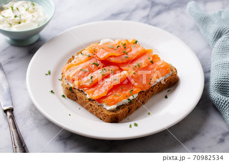 Sandwich, toast with smoked salmon and cream cheese on white plate. Marble background. Close up. Sandwich, toast with smoked salmon and cream cheese on white plate. Marble background. Close up. 70982534
