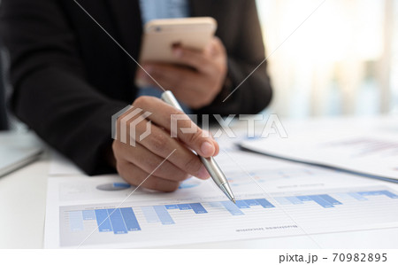 Financial businessmen use mobile phones to calculate income and analyze data about the company's financial performance to prepare for presentation to customers, Tax and accounting system concept. Financial businessmen use mobile phones to calculate income and analyze data about the company's financial performance to prepare for presentation to customers, Tax and accounting system concept. 70982895