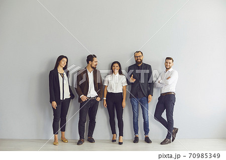 Group of happy young business people standing near studio wall looking at camera 70985349