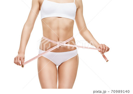Slim tanned woman's body isolated on white background - waist measurement 70989140