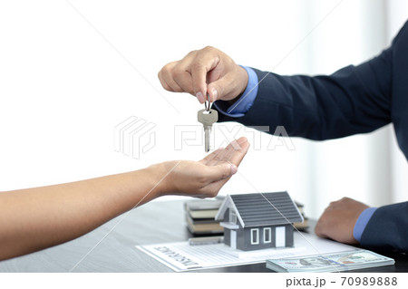 Sales manager or real estate agent holds the key handing it to the customer after signing the house purchase contract with home insurance, Trading of mortgages and insurance concept. 70989888