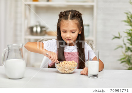 cute little girl eating breakfast: cereal with the milk cute little girl eating breakfast: cereal with the milk 70992771