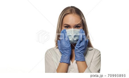 Young nurse with long hair in mask looking straight. Young nurse with long hair in mask looking straight. 70993893