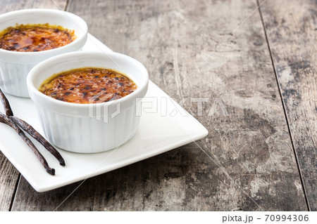 Traditional French creme brulee dessert with caramelized sugar on top, on wooden table	 70994306