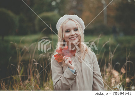 Smiling autumn woman holding autumn leaves on fall nature background 70994943