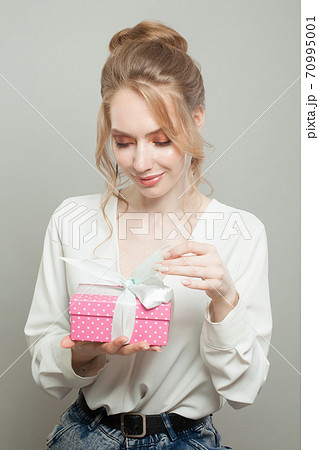 Cheerful woman holding pink gift on white background 70995001