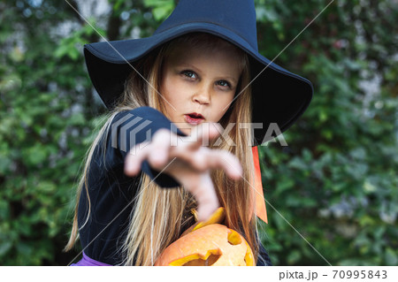 Little girl in witch costume having fun on Halloween trick or treat 70995843