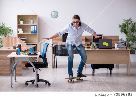 Young male employee with skateboard in the office 70996392