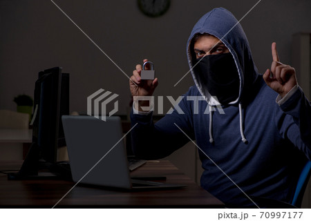 Male hacker hacking security firewall late in office 70997177