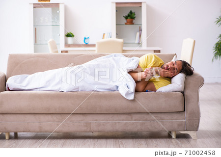 Ill young man lying on the sofa at home Ill young man lying on the sofa at home 71002458