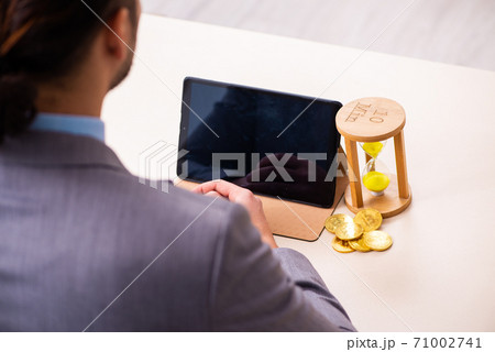 Young man earning money via Internet in time management concept 71002741