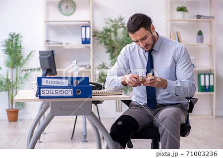 Young leg injured employee working in the office 71003236
