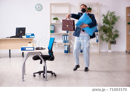 Young male employee during pandemic at workplace 71003570