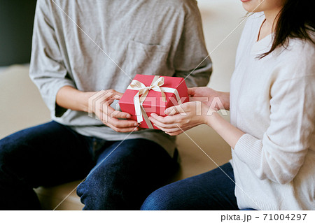 女性にプレゼントを渡す男性 女性にプレゼントを渡す男性 71004297