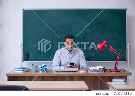 Young male teacher in front of green board 71004310