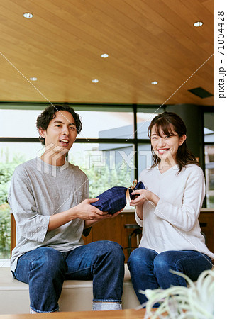 男性にプレゼントを渡す女性 男性にプレゼントを渡す女性 71004428