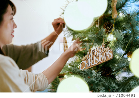 クリスマスツリーに飾り付けをする女性 クリスマスツリーに飾り付けをする女性 71004491