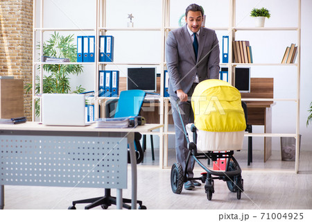 Young male employee looking after newborn at workplace Young male employee looking after newborn at workplace 71004925