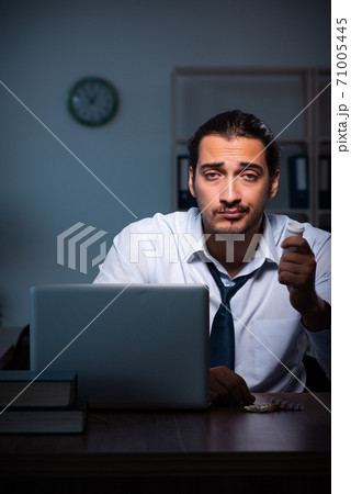 Young male employee working in the office night time 71005445