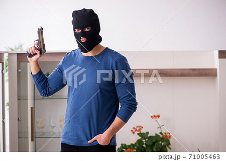 Male robber stealing valuable things from the house 71005463