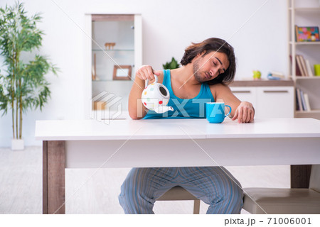 Young man waking up at home 71006001