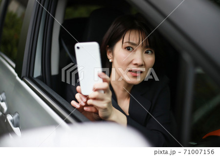慌ててスマートフォンで撮影する女性 71007156