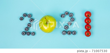 2021 Happy New Year and New You with fruit and vegetable; Blueberries, green apple and Tomato on blue background. Goals, Healthy, Resolution, Time to New Start and dieting concept 71007530