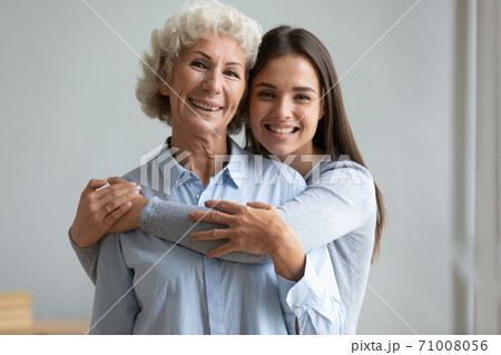 Beautiful adult daughter hug older mother at home, portrait Beautiful adult daughter hug older mother at home, portrait 71008056